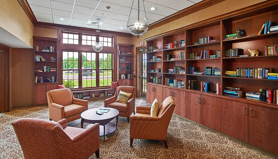 A lounge area with vaulted ceilings a fireplace with chairs, sofas, and tables