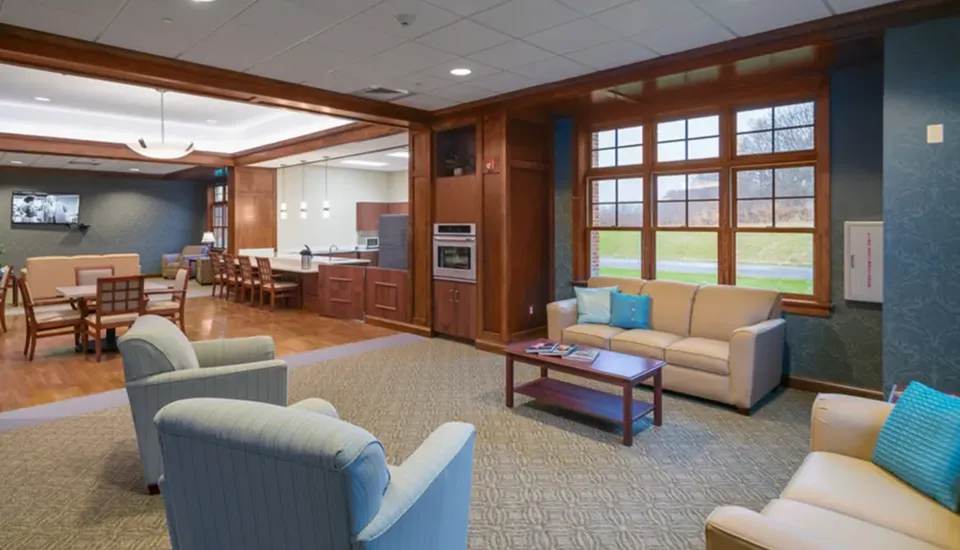 A lounge area with vaulted ceilings a fireplace with chairs, sofas, and tables