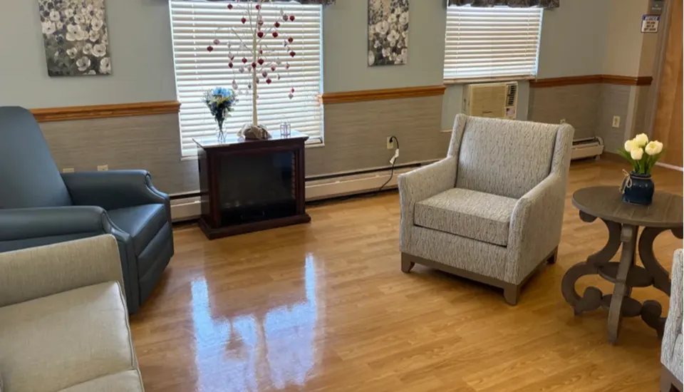 A lounge area with vaulted ceilings a fireplace with chairs, sofas, and tables