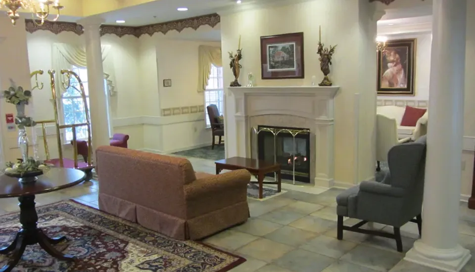 A lounge area with vaulted ceilings a fireplace with chairs, sofas, and tables