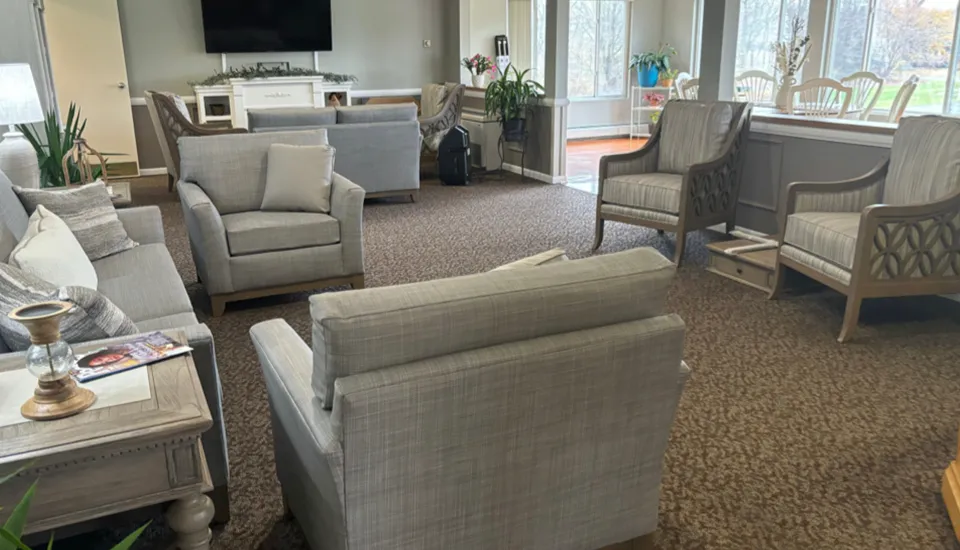 A lounge area with vaulted ceilings a fireplace with chairs, sofas, and tables