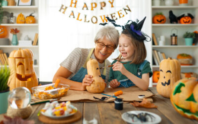 Grandmother and granddaughter painting pumpkins on Halloween